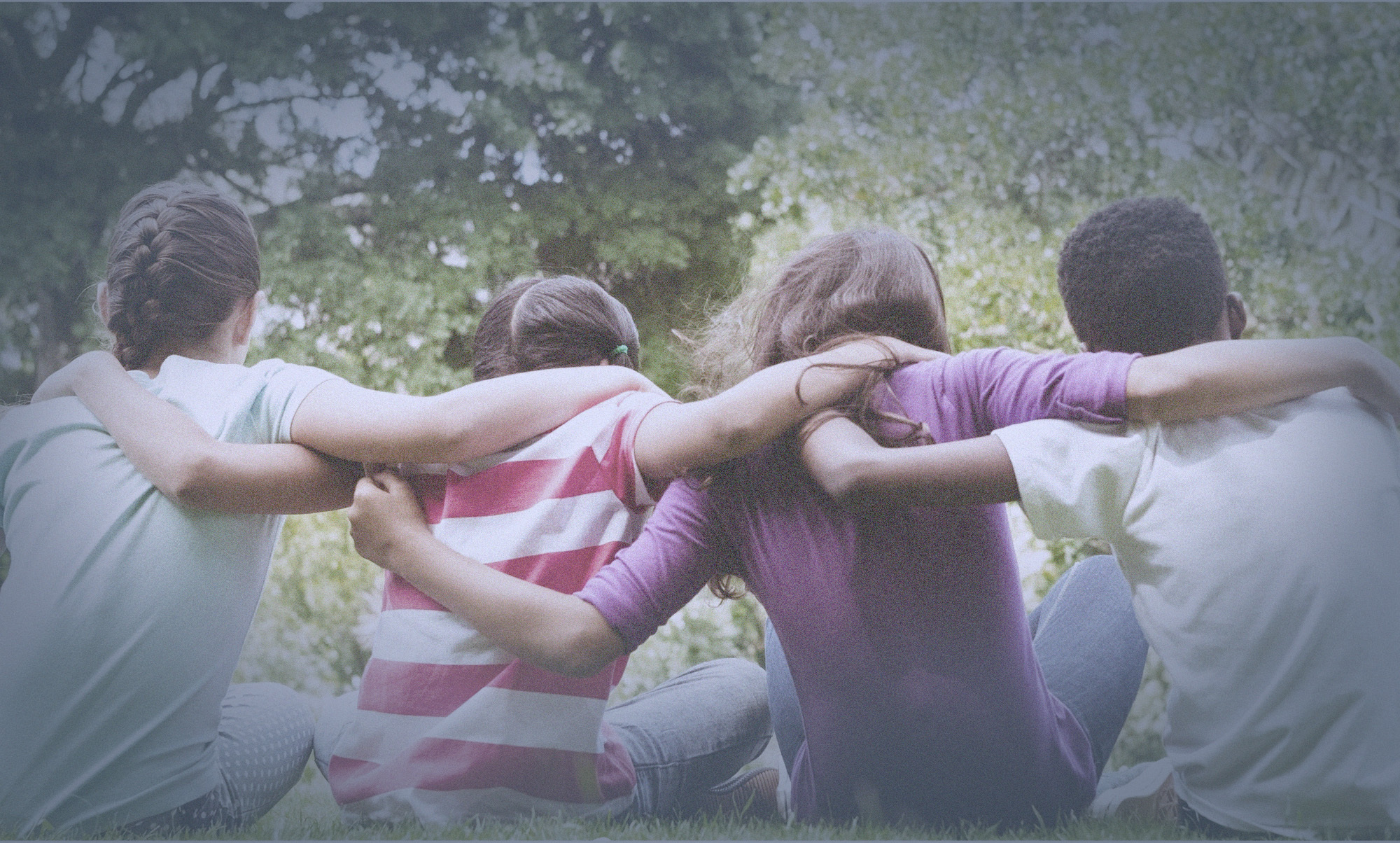 Four older children sitting on grass, facing away from camera, with arms around each other, with words, 